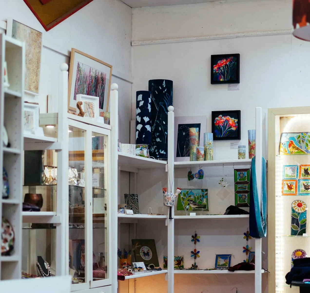 Kleiner, voller Laden mit weißen Regalen, Bildern an der Wand und Dekoration, die von der Decke hängt